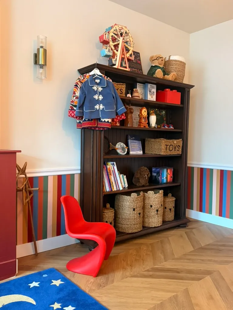 Een donkere houten boekenkast met boeken en gevlochten manden naast een rode kuipstoel