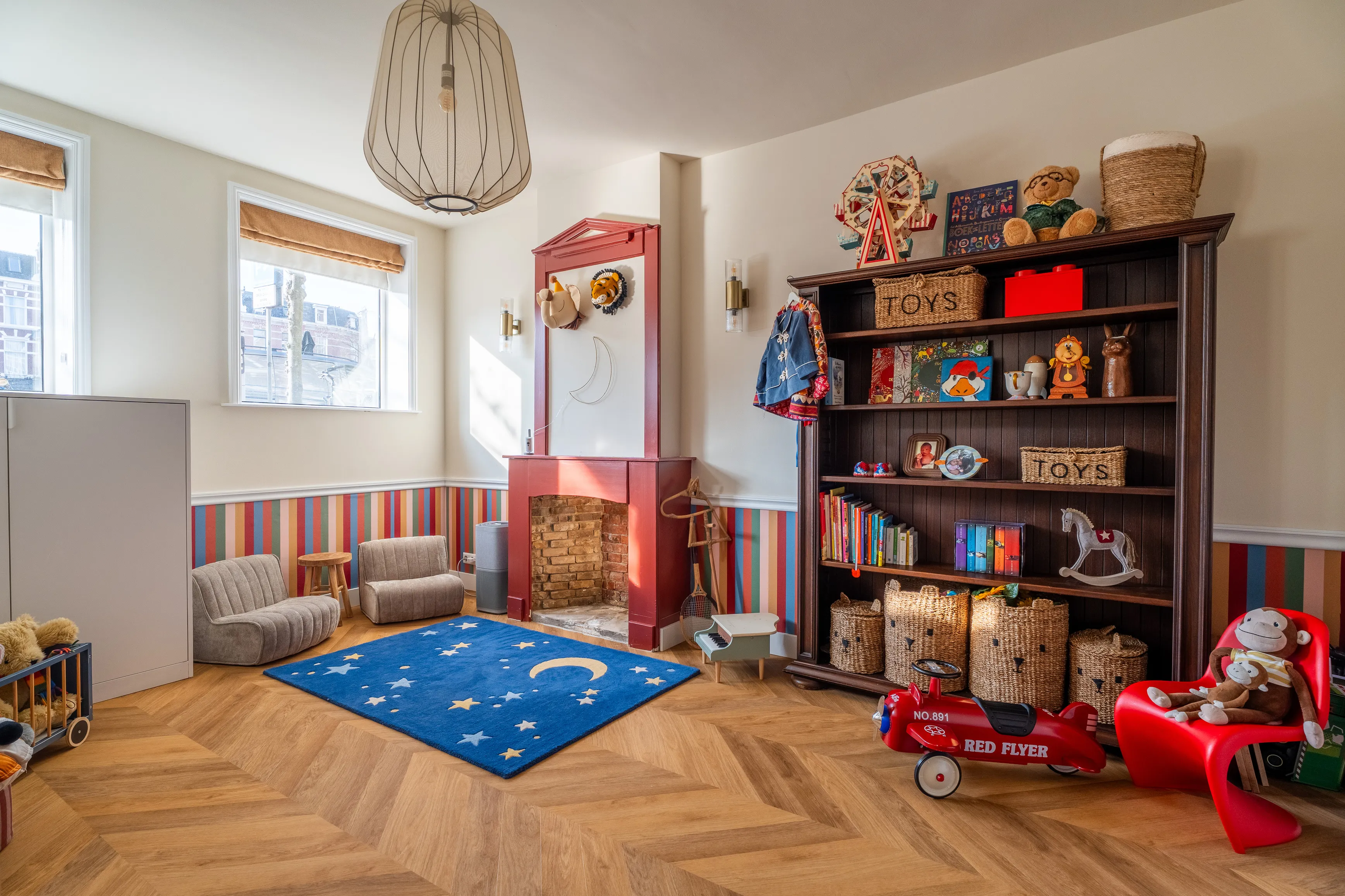 De Carrouselkamer, een warme speelkamer met gestreepte muren, een rode schouw en een boekenkast vol speelgoed